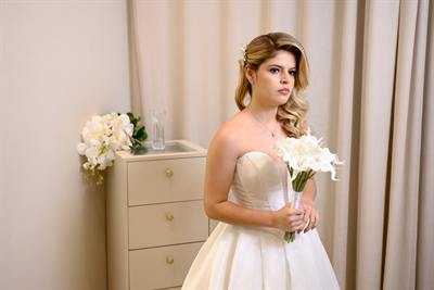 Noiva pronta segurando o buquê no quarto de preparação
